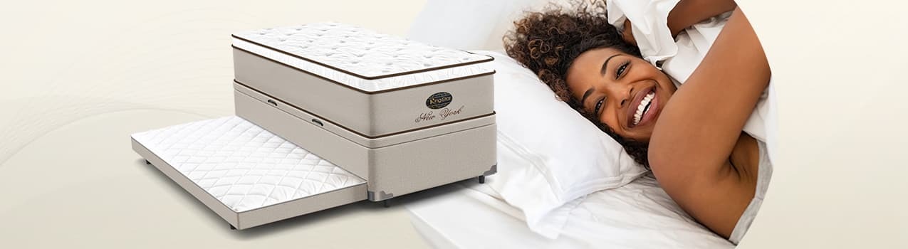 Montagem com um modelo de bicama com baú da King Star à esquerda e imagem de mulher negra deitada em cama sorrindo. Montagem com um modelo de bicama com baú da King Star à esquerda e imagem de mulher negra deitada em cama sorrindo
